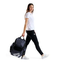 Load image into Gallery viewer, Woman holding a navy blue backpack with Arena logo on a white background