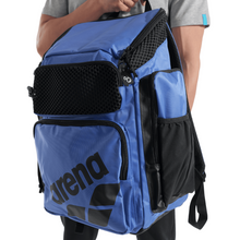 Load image into Gallery viewer, Blue backpack with black accents held by a person on a white background