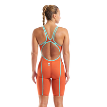 Load image into Gallery viewer, Woman wearing an orange and teal open back kneeskin racing suit with teal taping